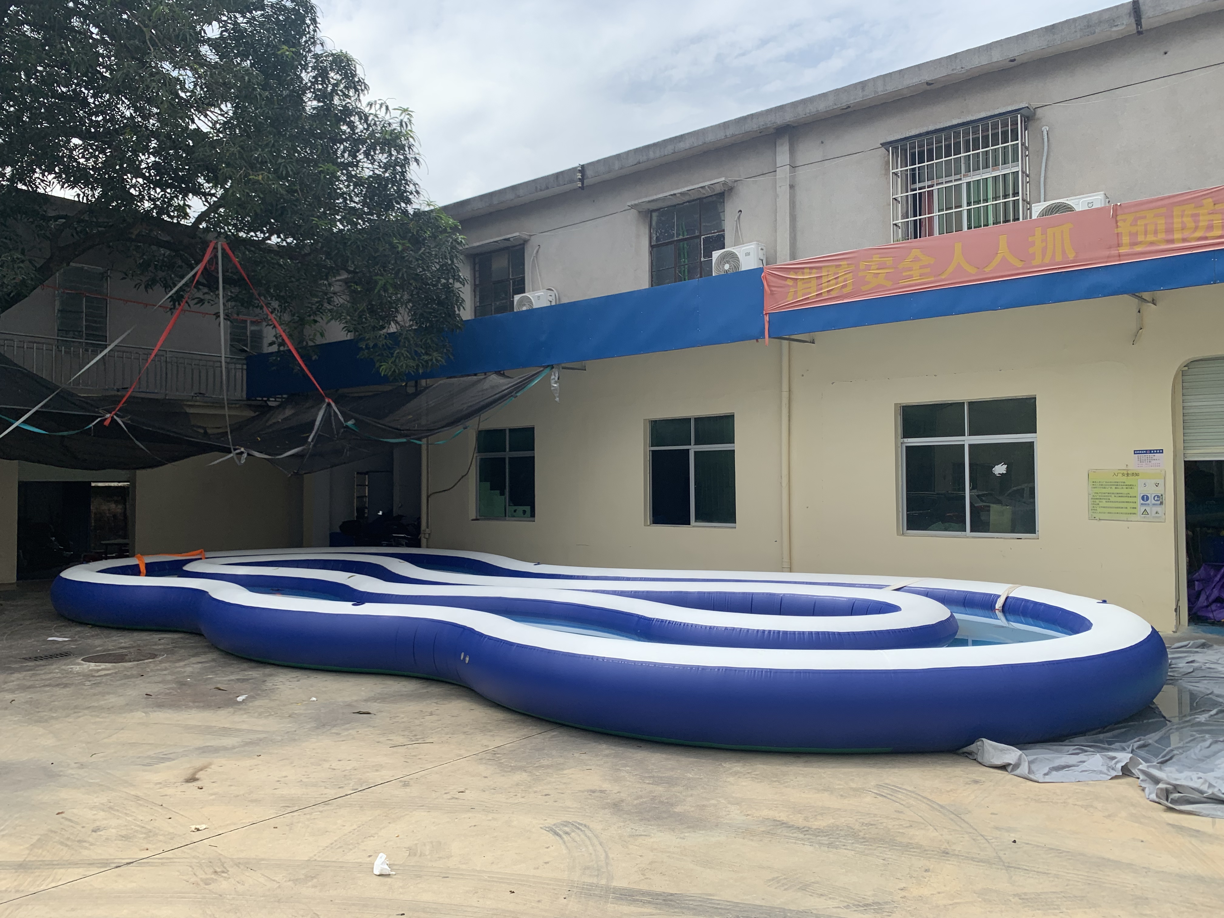 Inflatable lazy river filled with water winding through an open yard.