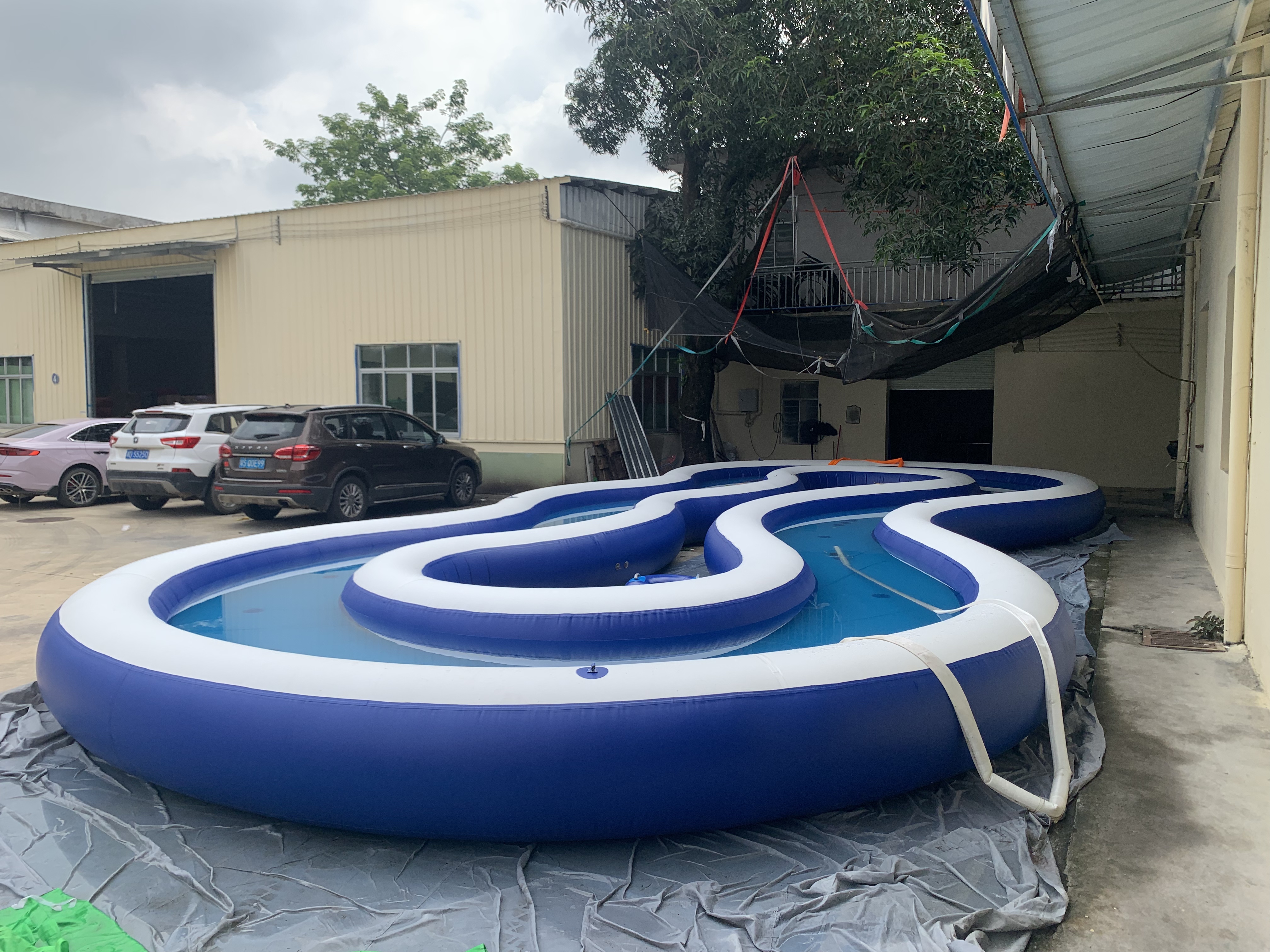 Wide view of a commercial inflatable lazy river set up on a tarp outdoors.