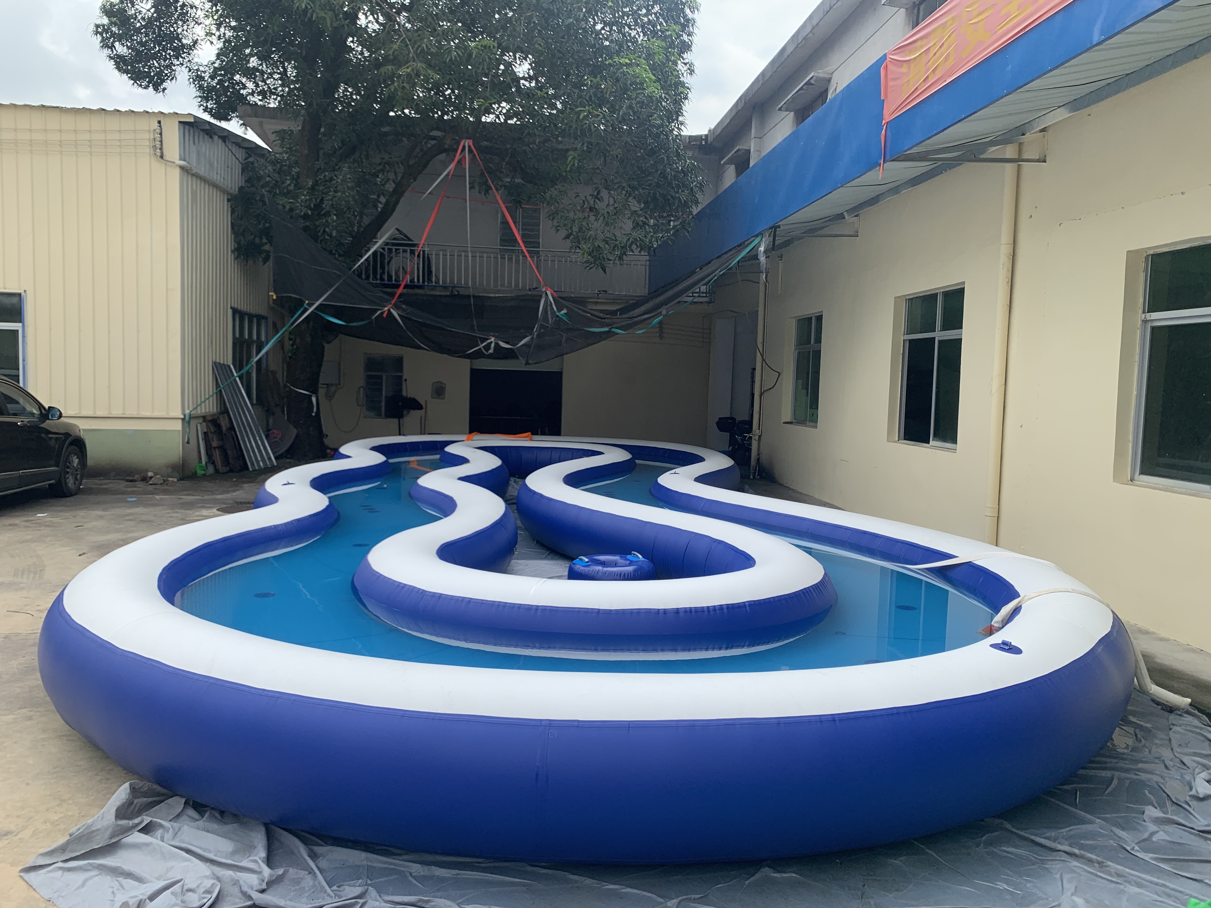 Long inflatable water course forming a lazy river between two buildings.